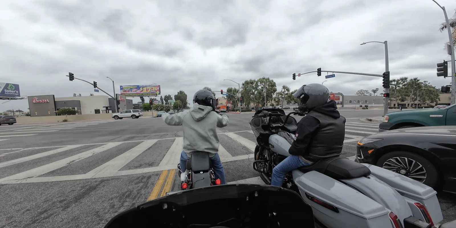 Two motorcycle riders waiting at an intersection on a group ride