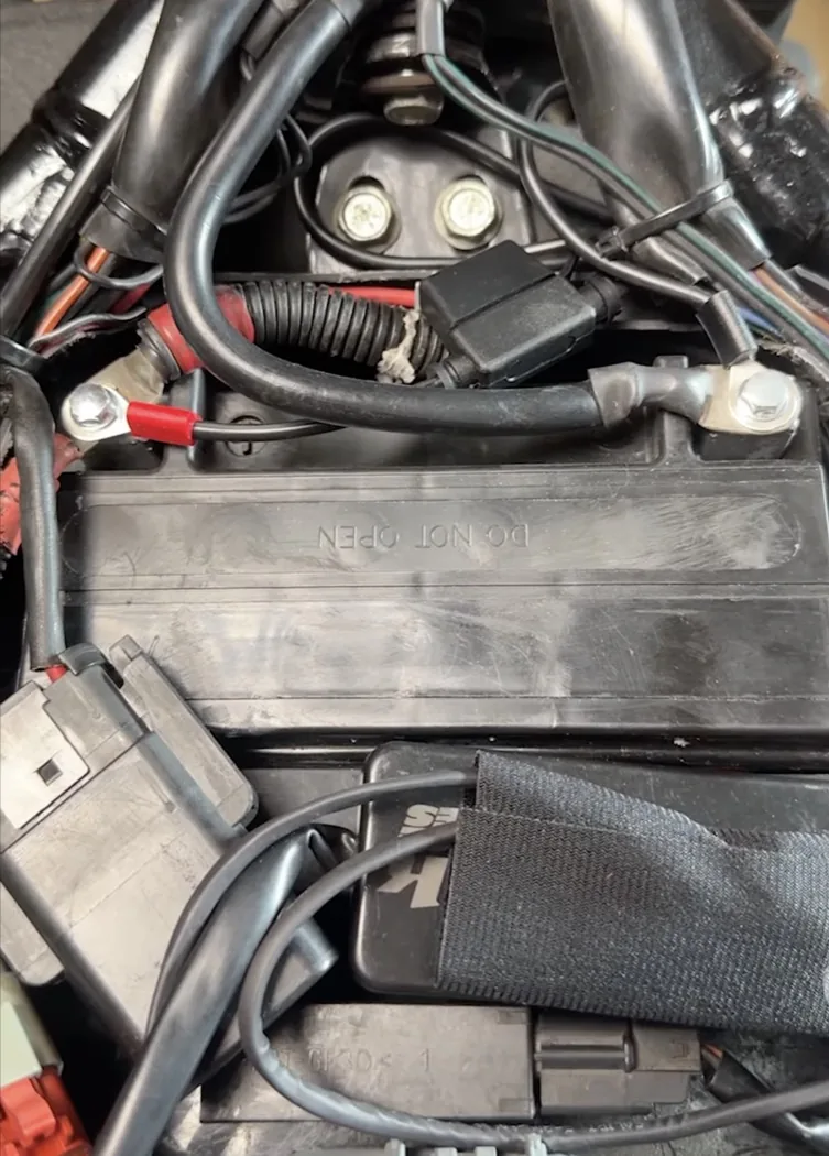 Close-up of a Harley battery, its terminals, and a battery tender harness pigtail