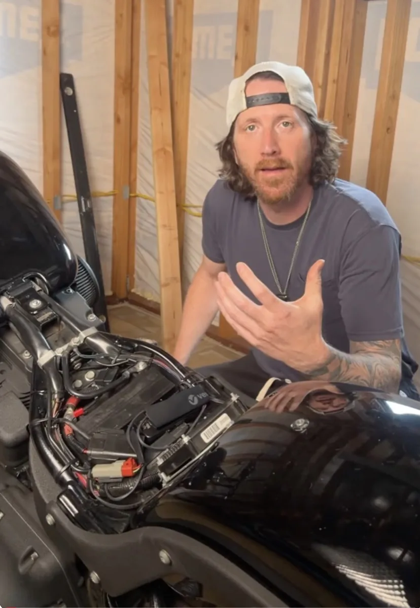 RideWolf founder Johnny checking the battery on his Harley with the seat removed