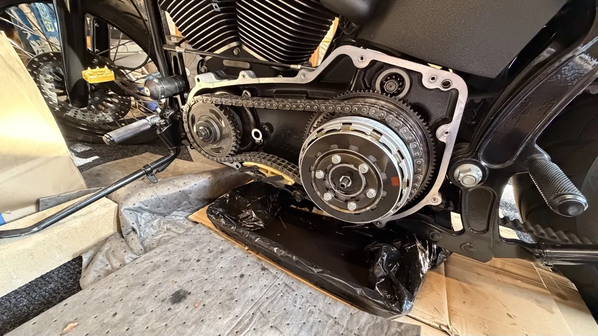 Open primary drive on a Harley showing the clutch pack and drive chain during a garage teardown