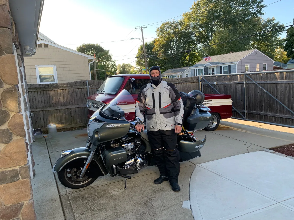 Rider in full layered cold-weather gear and balaclava beside an Indian Roadmaster before a long trip